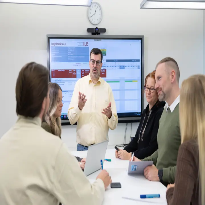 Unscharfes Bild mit einem Menschen vor einem projizierten Bühnenbild und Publikum