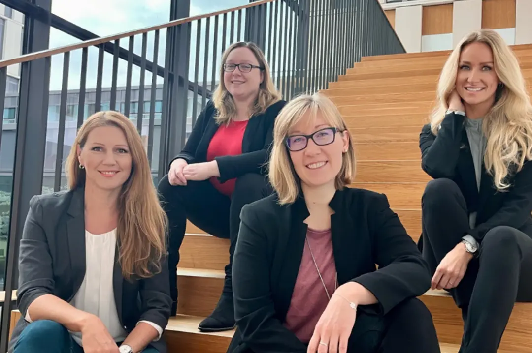 Unsere vier Mitarbeiterinnen sitzen auf einer Treppe